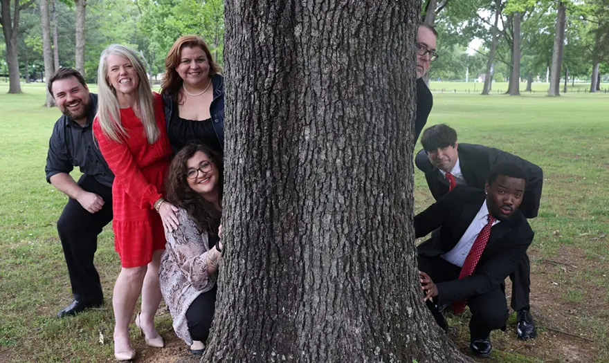 CRIS staff looking out at the camera from behind a tree