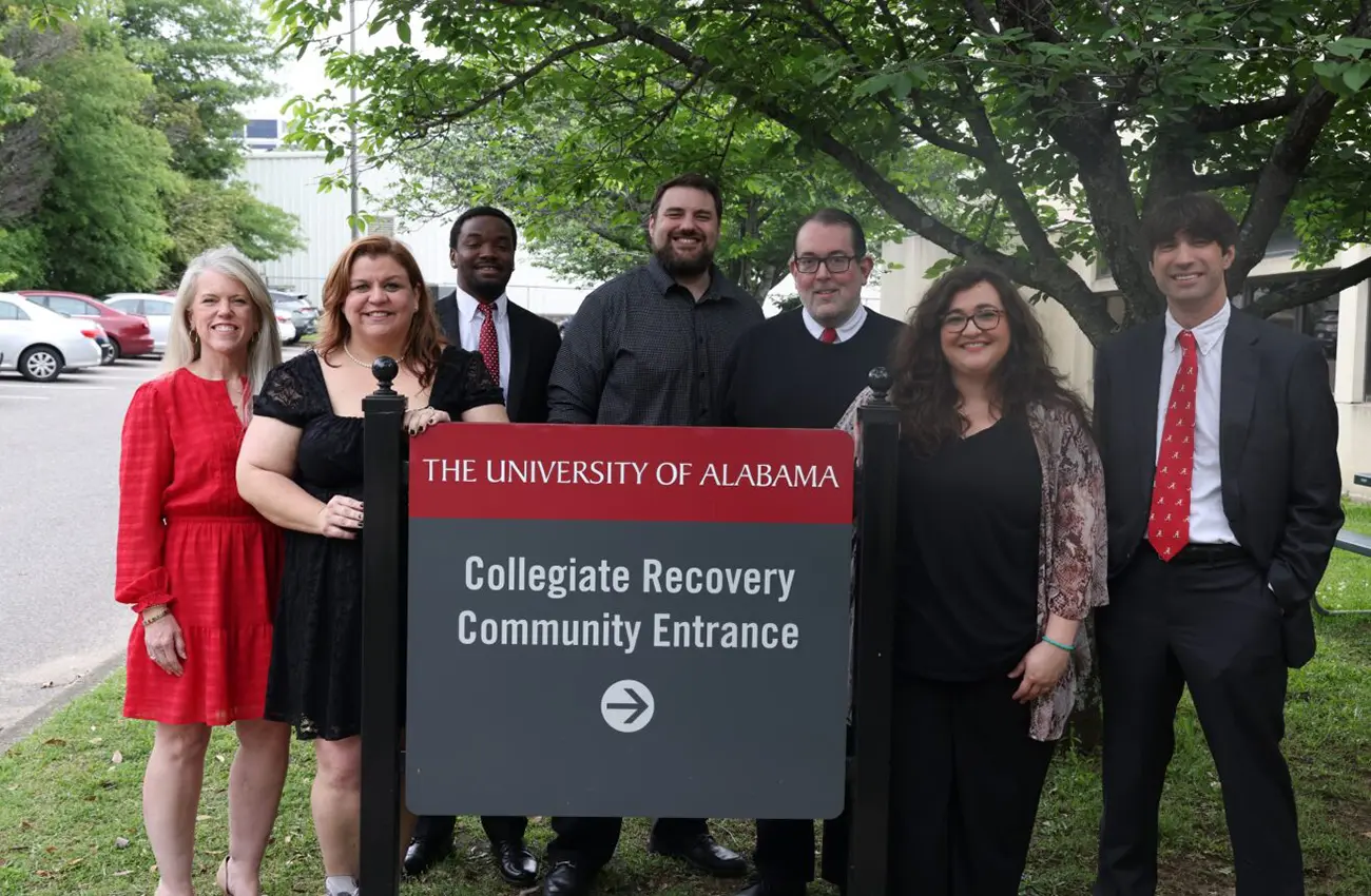 CRIS Staff by the Collegiate Recovery Community Entrance sign